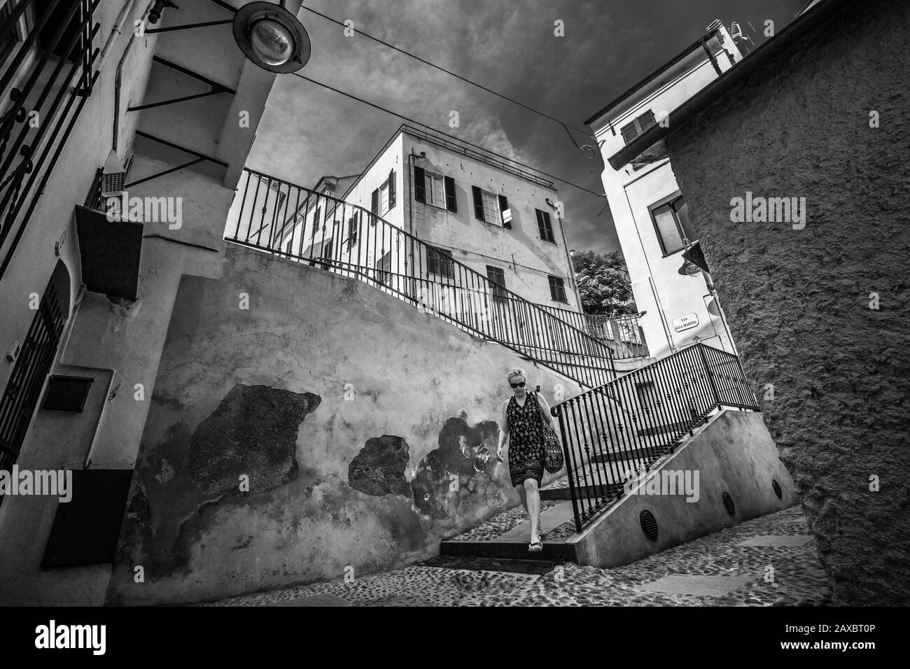 Borgio VEREZZI, ITALIEN - 30. Juli 2017: Schwarz-weiß einer Zitadinecke, Frau kommt die Treppe hinunter Stockfoto
