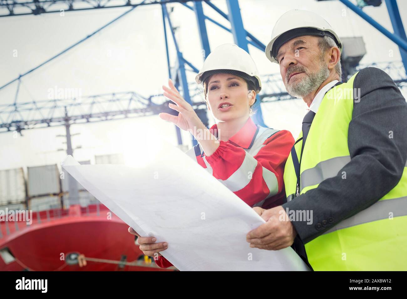 Hafenarbeiter und Manager mit Blueprint im Gespräch auf der Werft Stockfoto