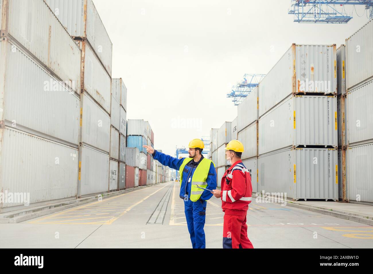 Hafenarbeiter sprechen zwischen Frachtcontainern auf der Werft Stockfoto