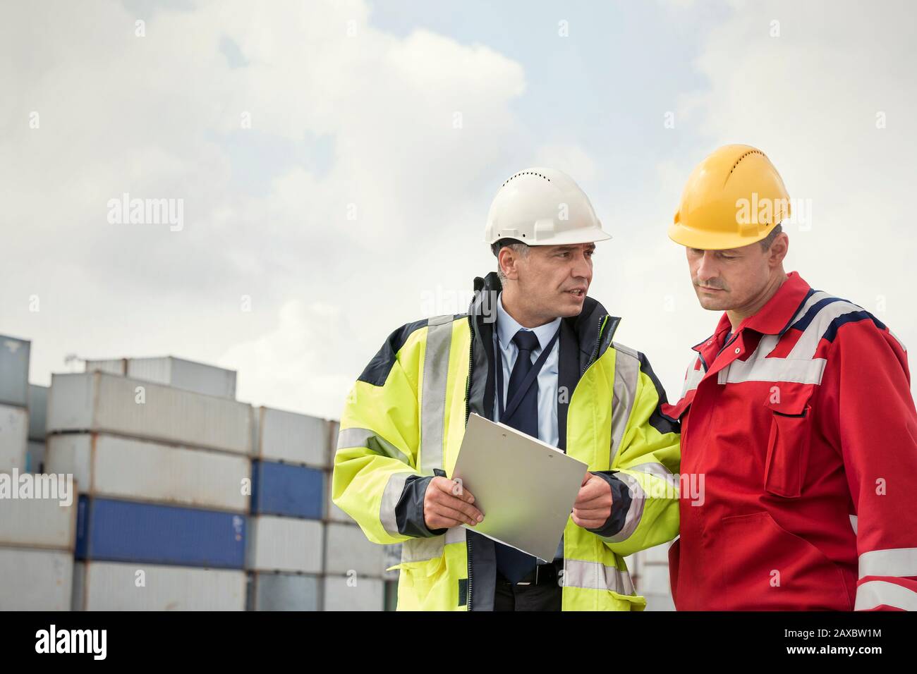 Hafenarbeiter und Manager mit Clipboard im Gespräch auf der Werft Stockfoto