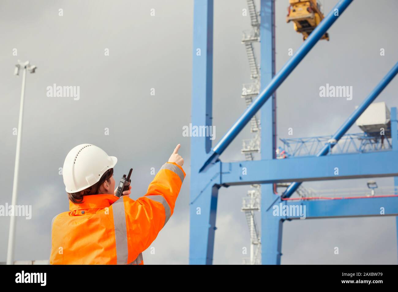 Hafenarbeiter mit Walkie-Talkie-Regie-Kran auf der Werft Stockfoto