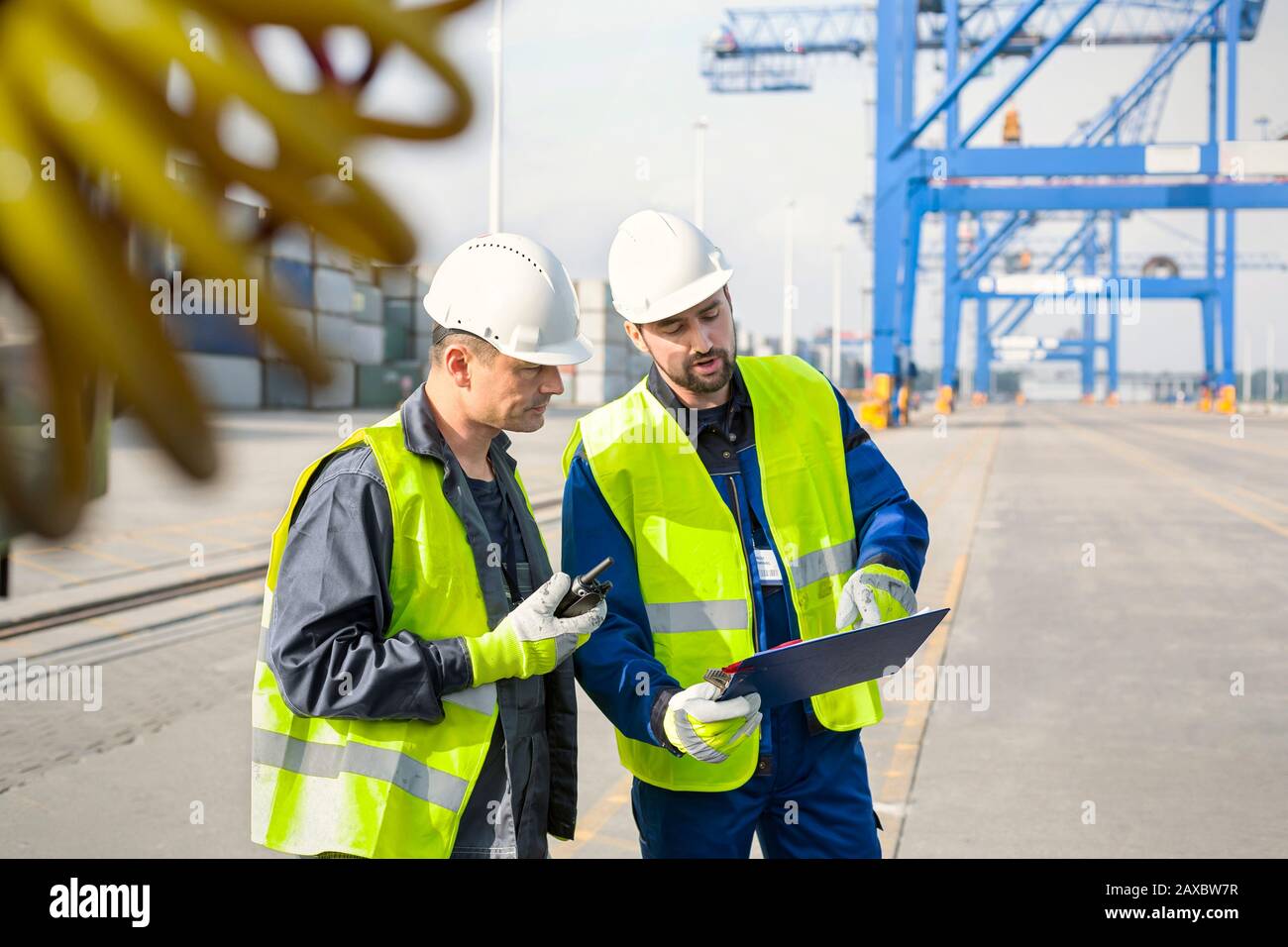 Hafenarbeiter mit Walkie-Talkie und Clipboard Meeting auf der Werft Stockfoto