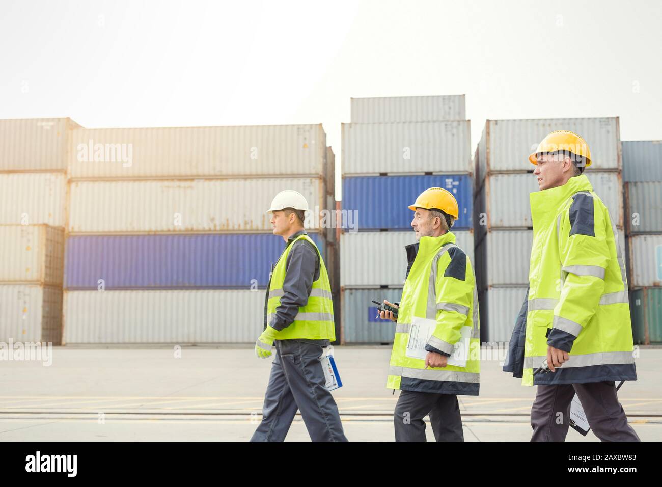 Hafenarbeiter, die auf der Werft in Frachtcontainern spazieren Stockfoto