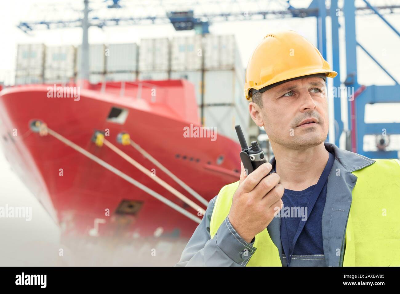 Hafenarbeiter mit Walkie-Talkie unterhalb des Containerschiffs auf der Werft Stockfoto