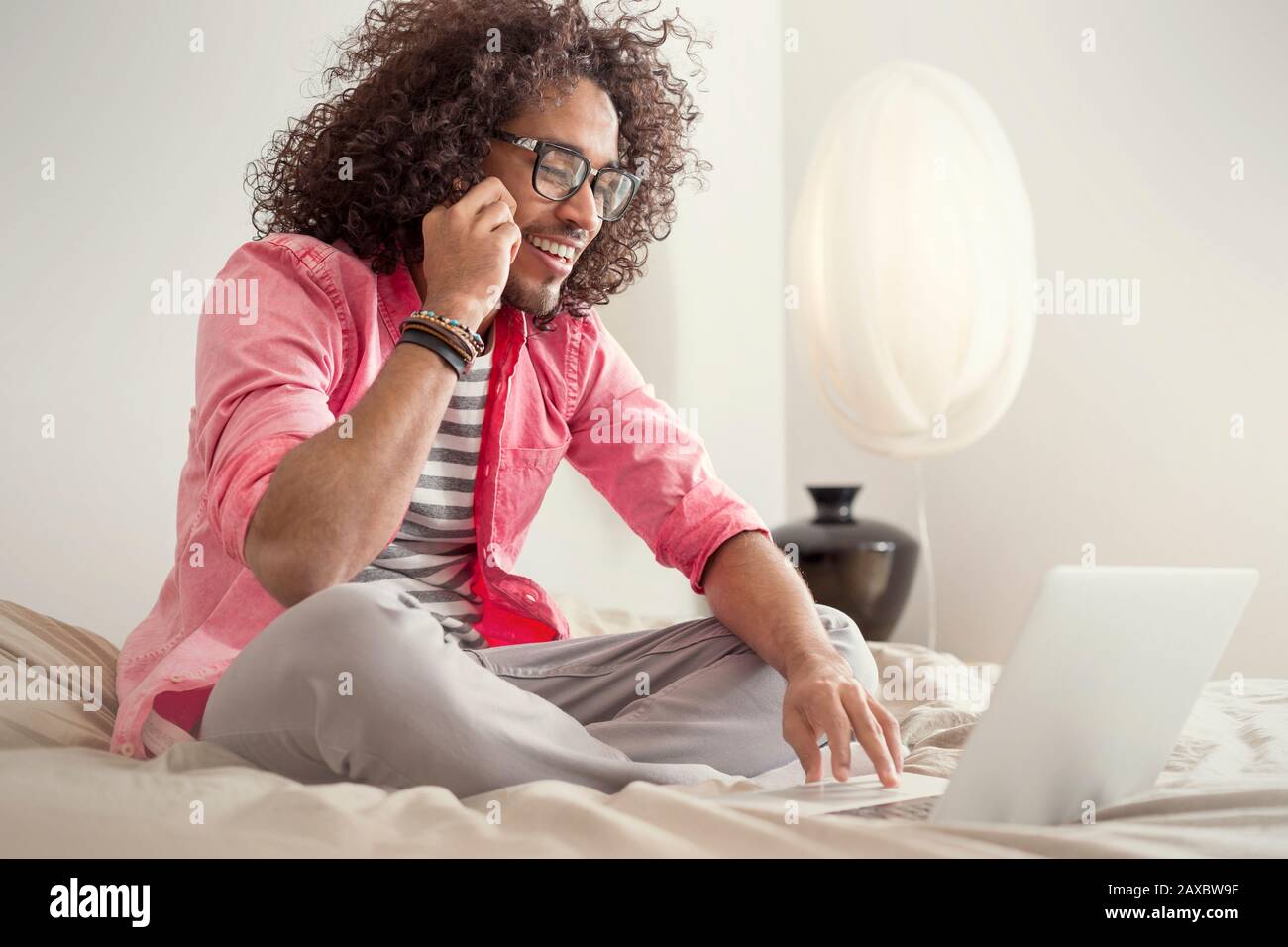 Glücklicher junger Mann mit Laptop am Bett Stockfoto