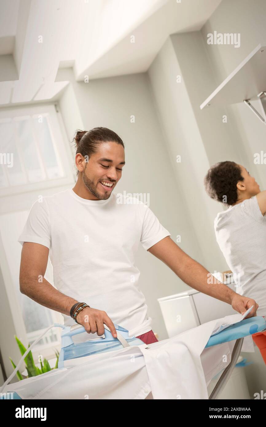 Junger Mann, der Wäsche macht, Bügelhemd in der Waschküche Stockfoto