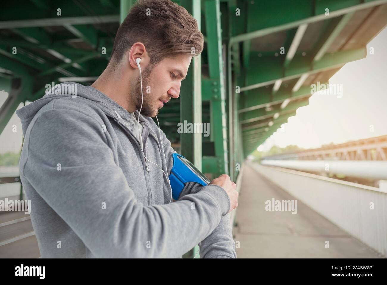 Junger männlicher Läufer, der Musik mit Kopfhörern und MP3-Player ARM Band hört Stockfoto