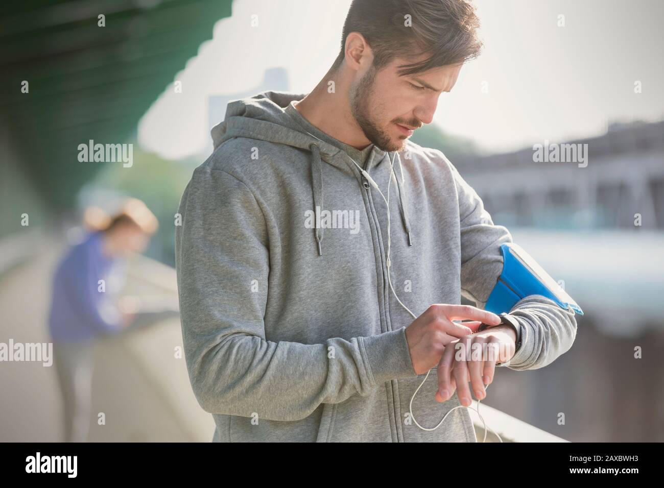 Junge männliche Läuferin überprüft intelligente Uhr Stockfoto