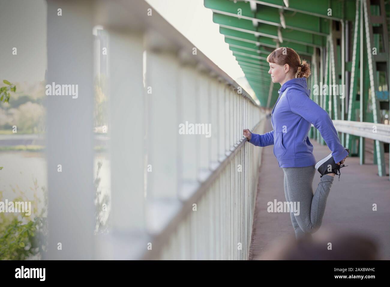 Junge weibliche Läuferin streckt sich das Bein am städtischen Geländer Stockfoto