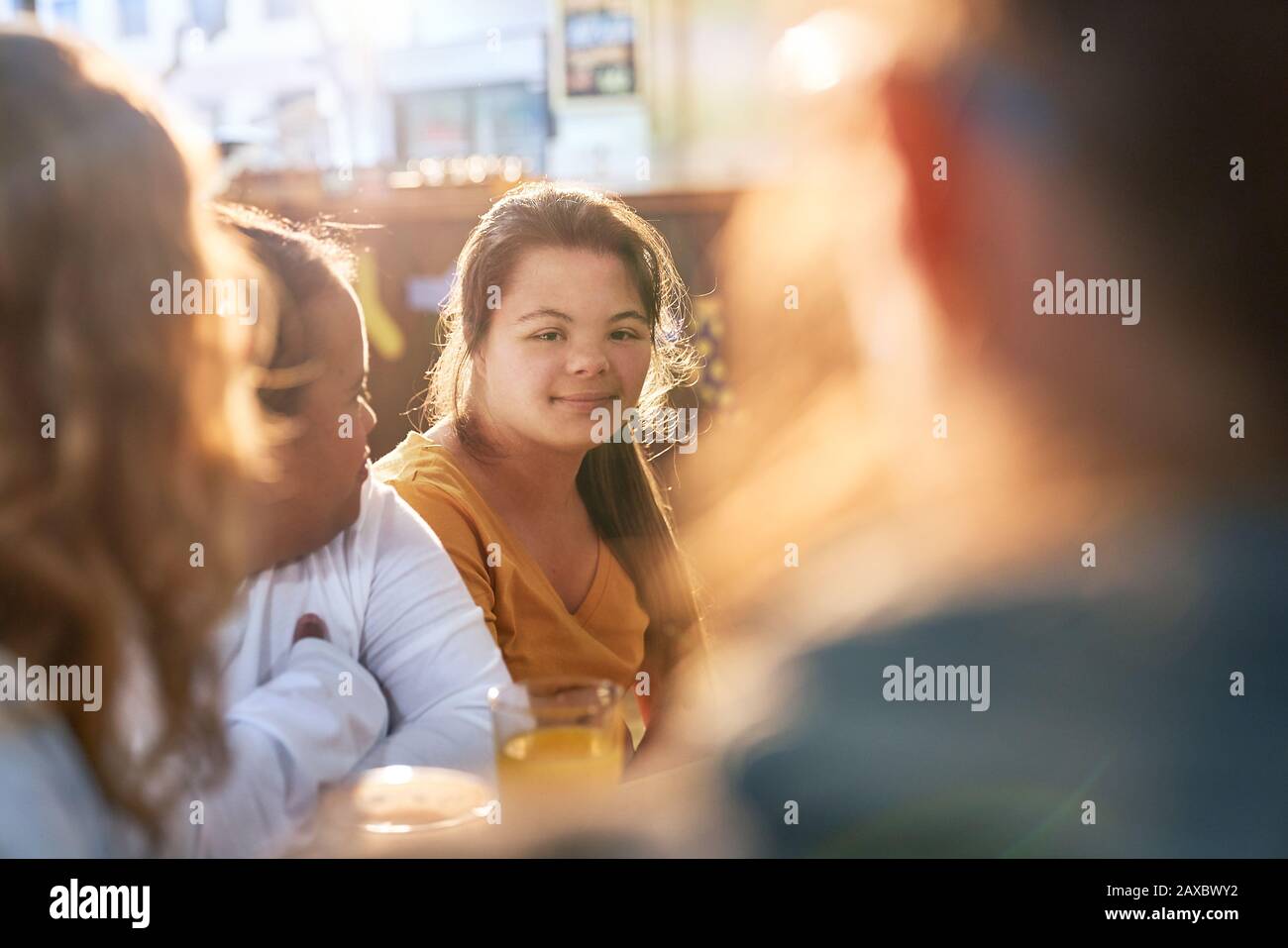 Portrait lächelnde junge Frau mit Down-Syndrom im Café mit Freunden Stockfoto