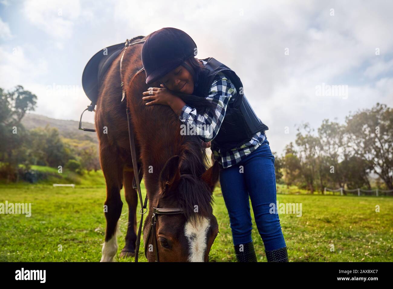 Glückliches Mädchen umarmte Pferd im Landrasen-Paddock Stockfoto