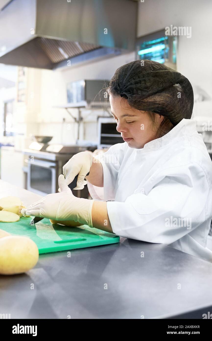 Fokussierte junge Frau mit Down-Syndrom-Kochen in der Café-Küche Stockfoto