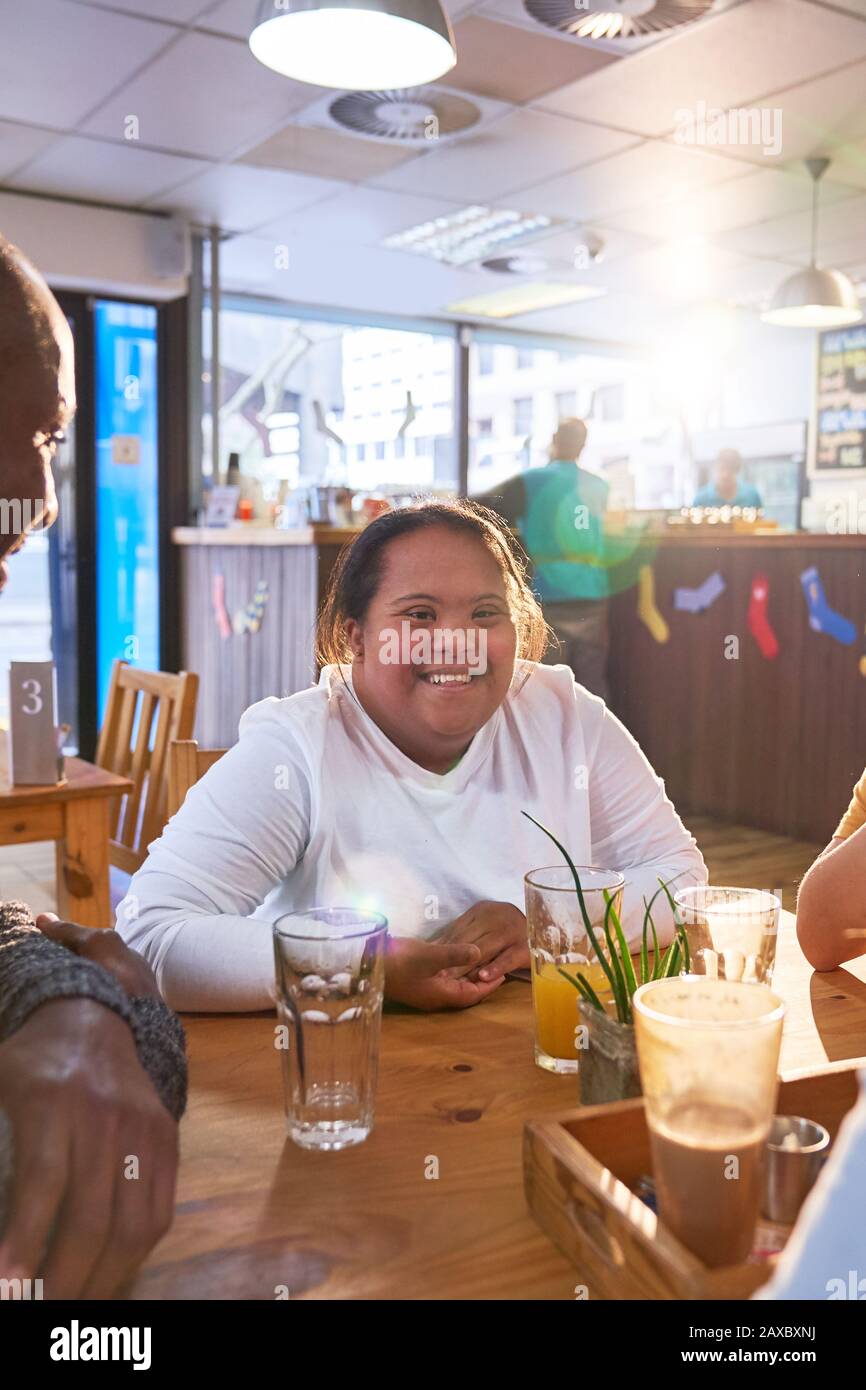 Portrait fröhliche junge Frau mit Down-Syndrom im Café mit Freunden Stockfoto