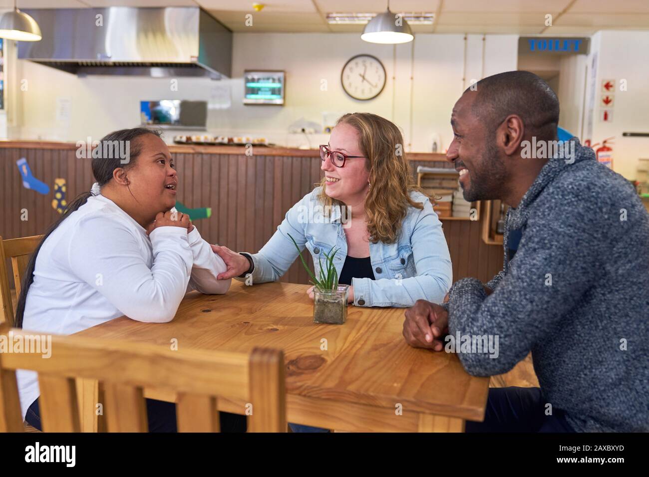 Eltern und Tochter mit Down-Syndrom sprechen im Café Stockfoto
