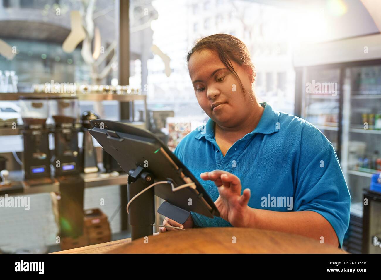 Junge Frau mit Down-Syndrom, die in der Kasse im Café arbeitet Stockfoto