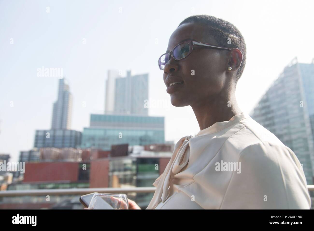 Ambitionierte, selbstbewusste Geschäftsfrau auf sonnigen, städtischen Balkon Stockfoto