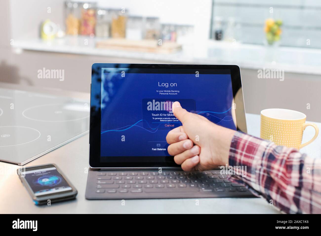 Personal Perspective man meldet sich mit Fingerabdruck in der Küche auf dem digitalen Tablet an Stockfoto