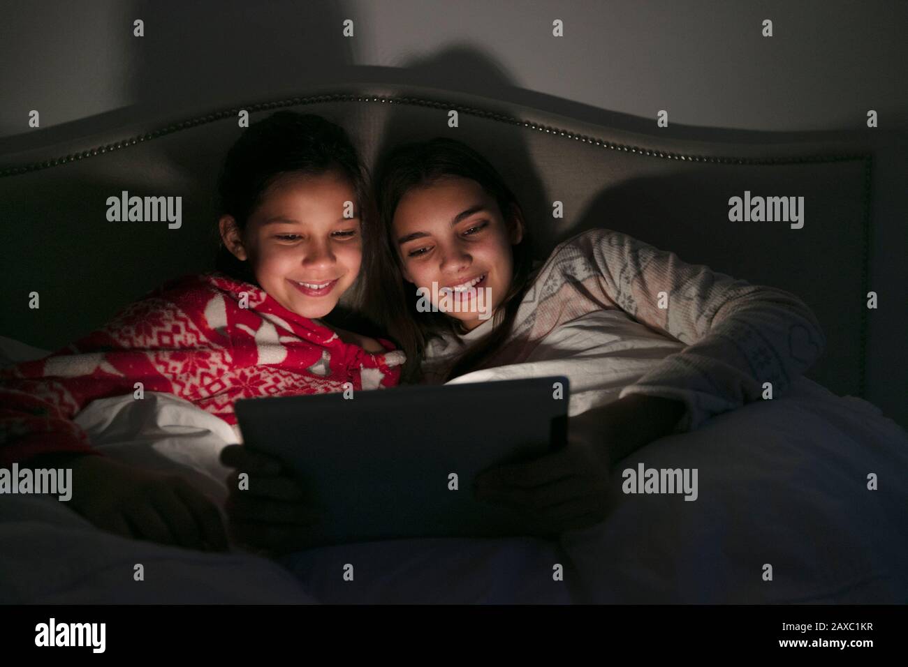 Mädchen, die Filme auf einem digitalen Tablet im dunklen Schlafzimmer ansehen Stockfoto