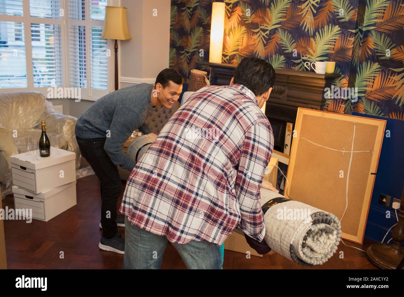 Männer ziehen Teppich in das Wohnzimmer des neuen Hauses Stockfoto
