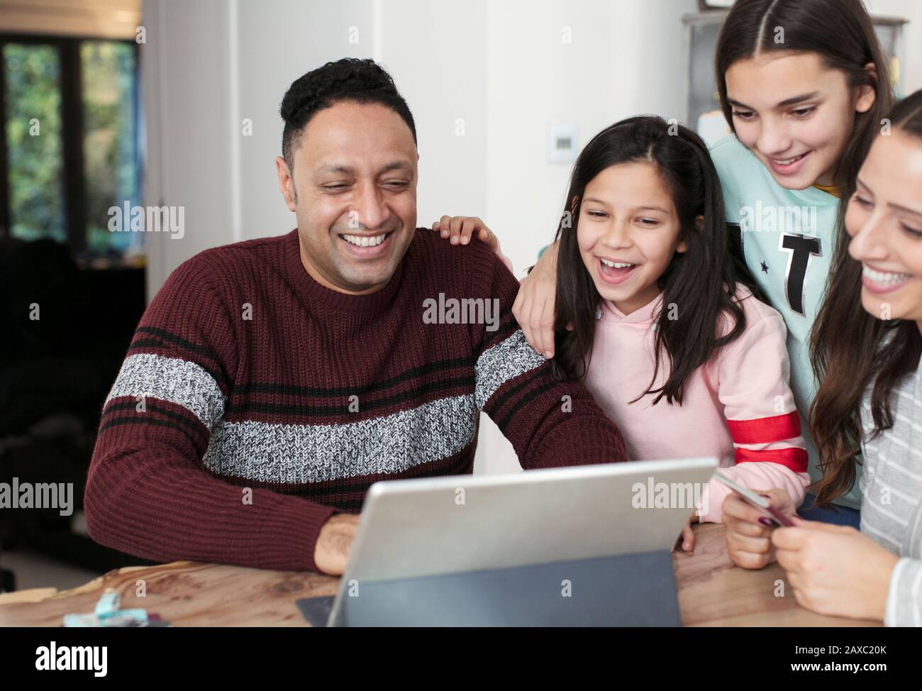 Eine glückliche Familie, die ein digitales Tablet am Tisch verwendet Stockfoto