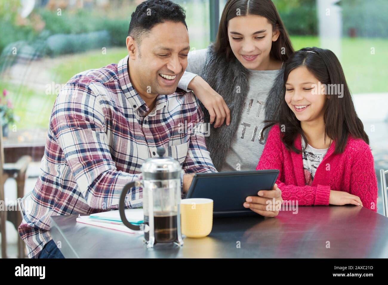 Glücklicher Vater und Töchter, die ein digitales Tablett in der Morgenküche verwenden Stockfoto