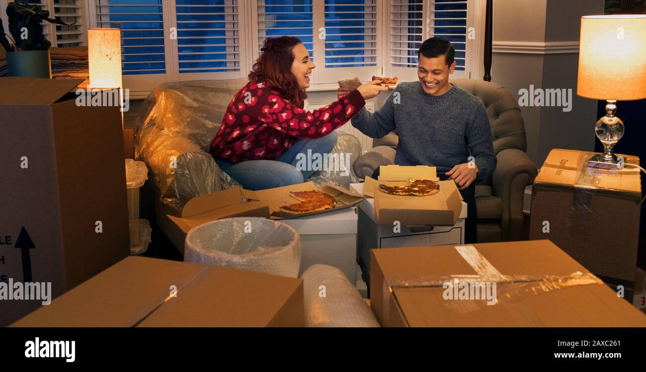 Glückliches Paar, das eine Pause von der Bewegung macht und Pizza isst Stockfoto