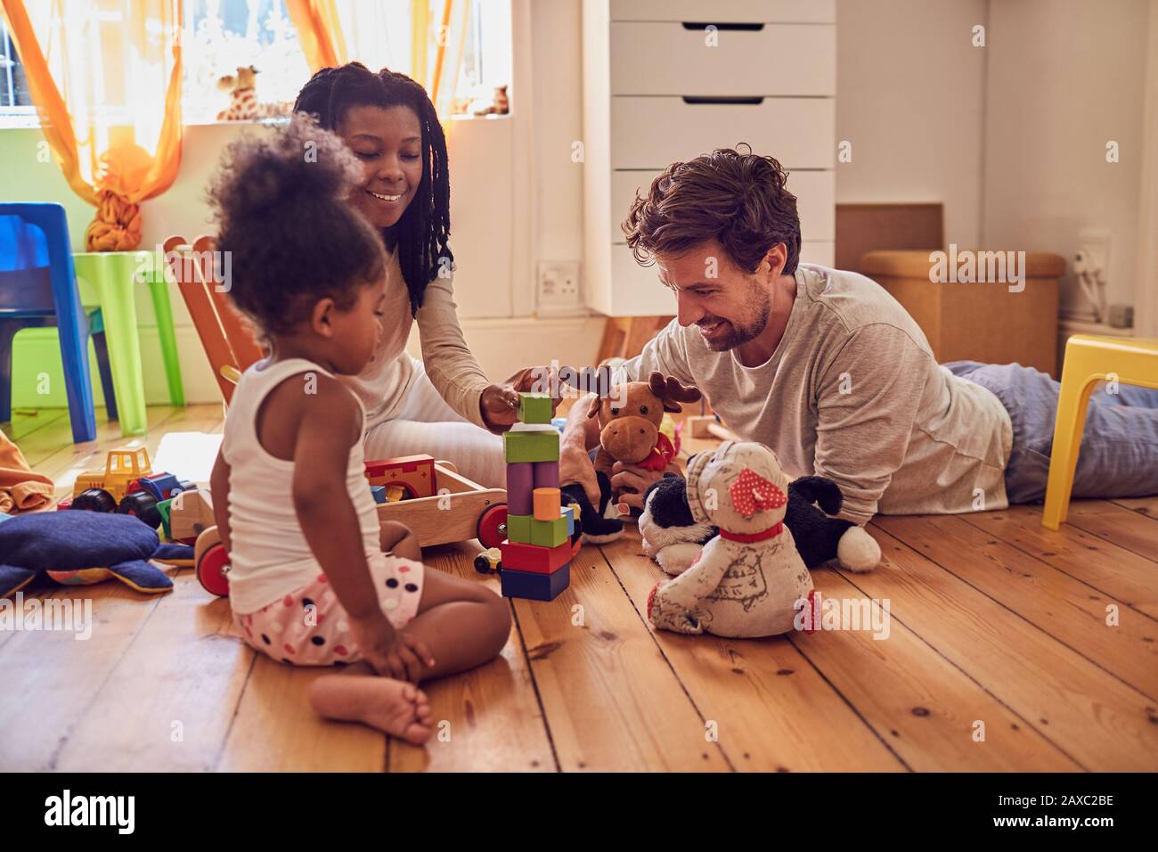 Junge Familie, die mit Spielzeug auf dem Boden spielt Stockfoto