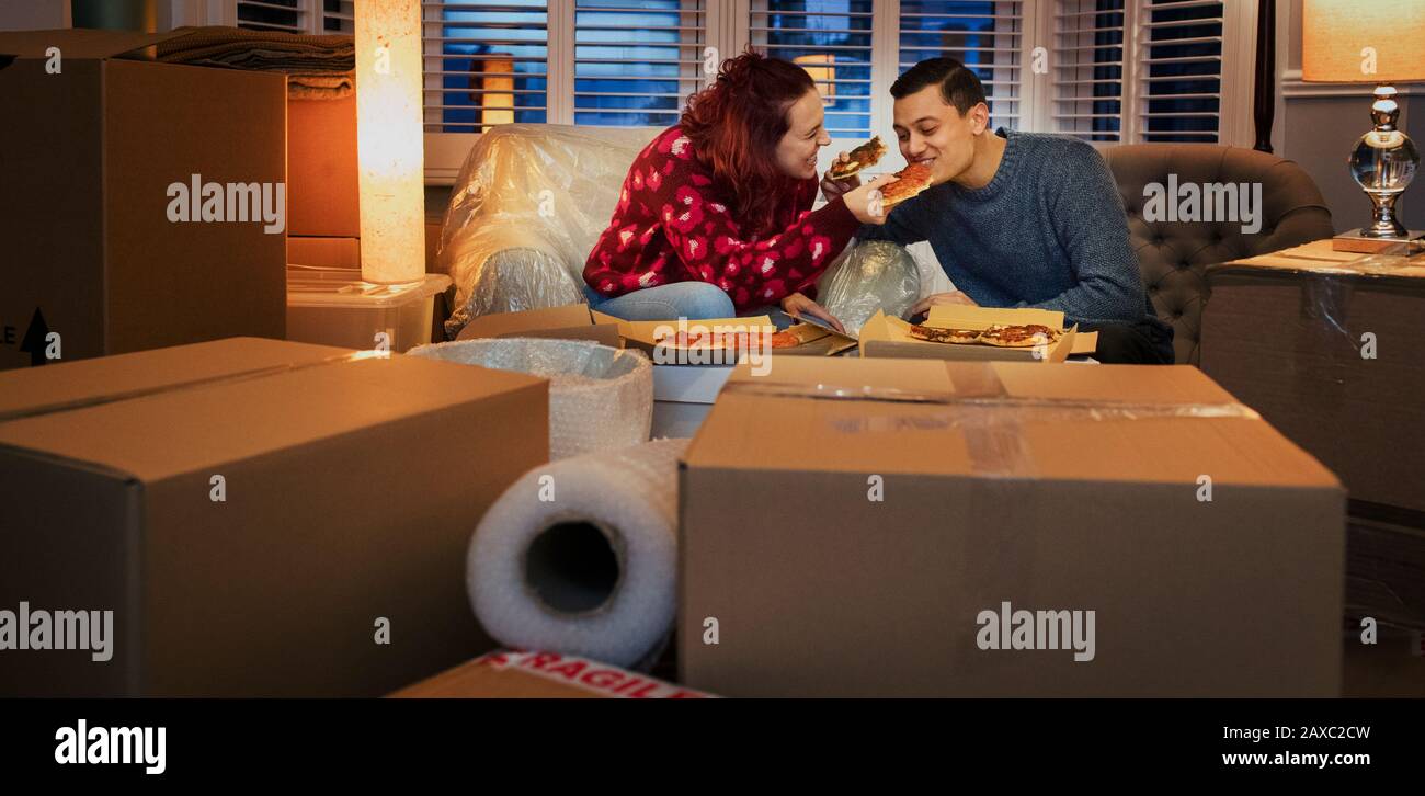 Ein Paar, das eine Pause vom Umzug nimmt und Pizza im Wohnzimmer isst Stockfoto
