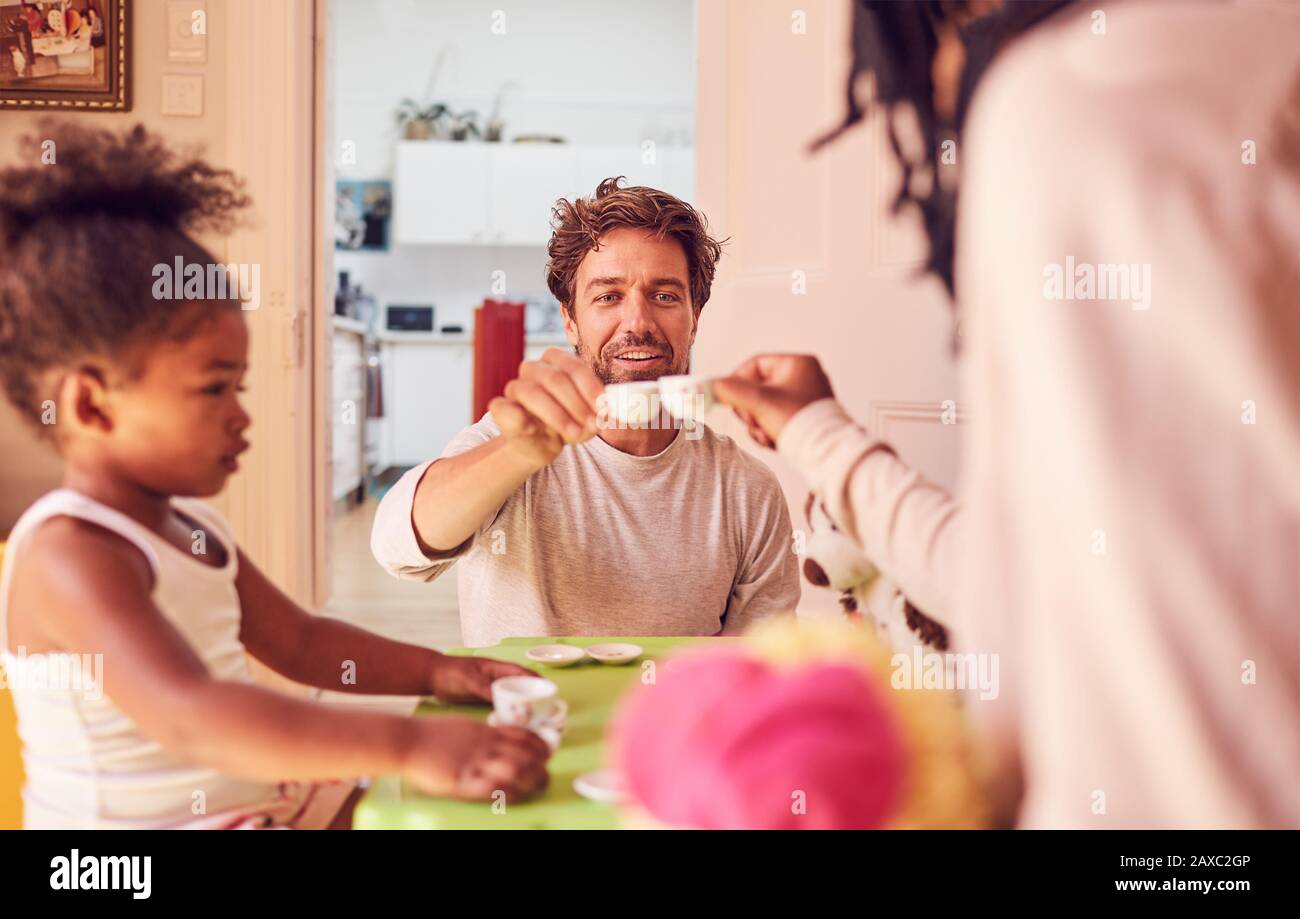 Junge Familie genießt imaginäre Teeparty Stockfoto
