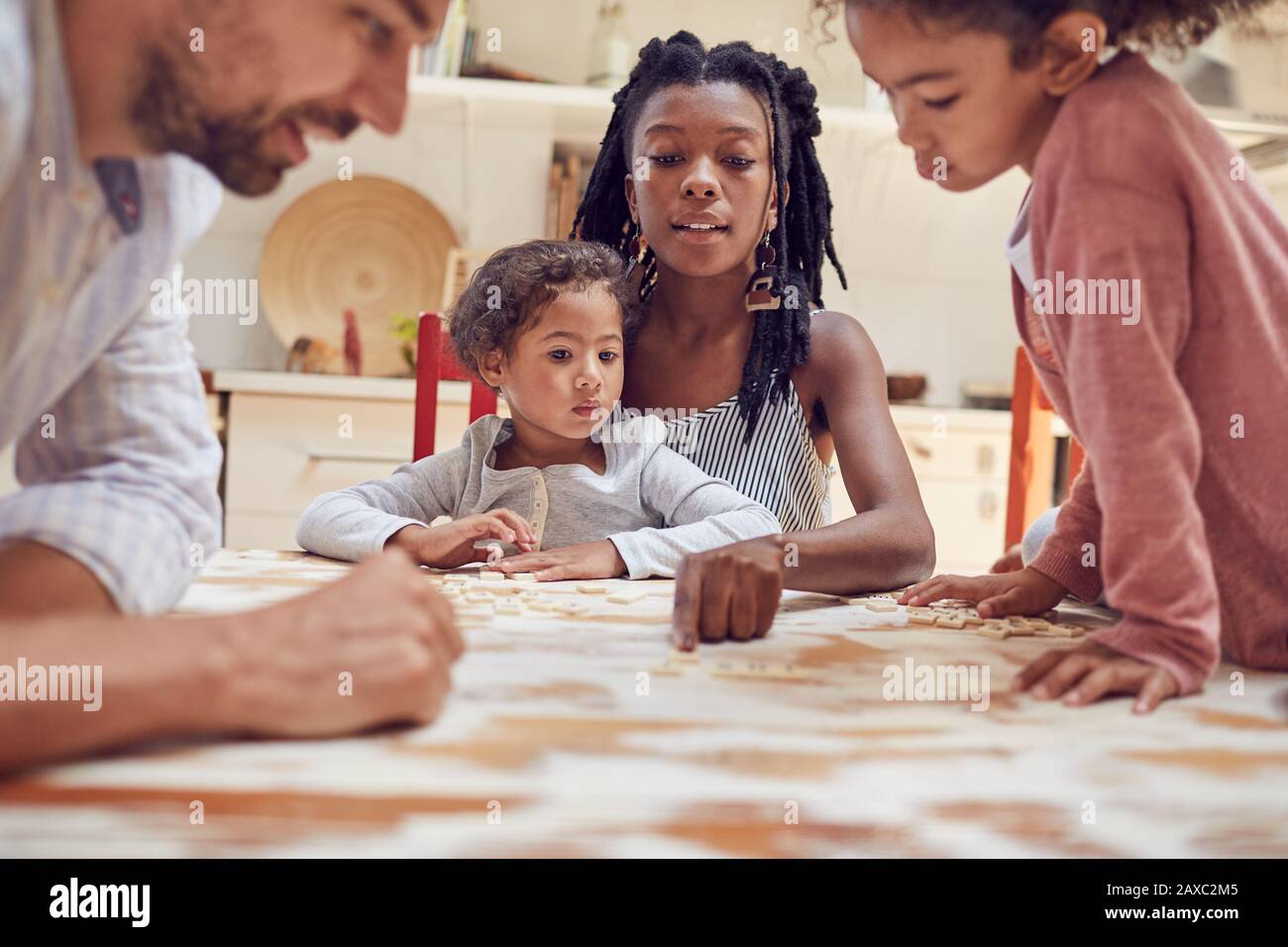 Junge Familie, die am Tisch ein fabeles Wortspiel spielt Stockfoto