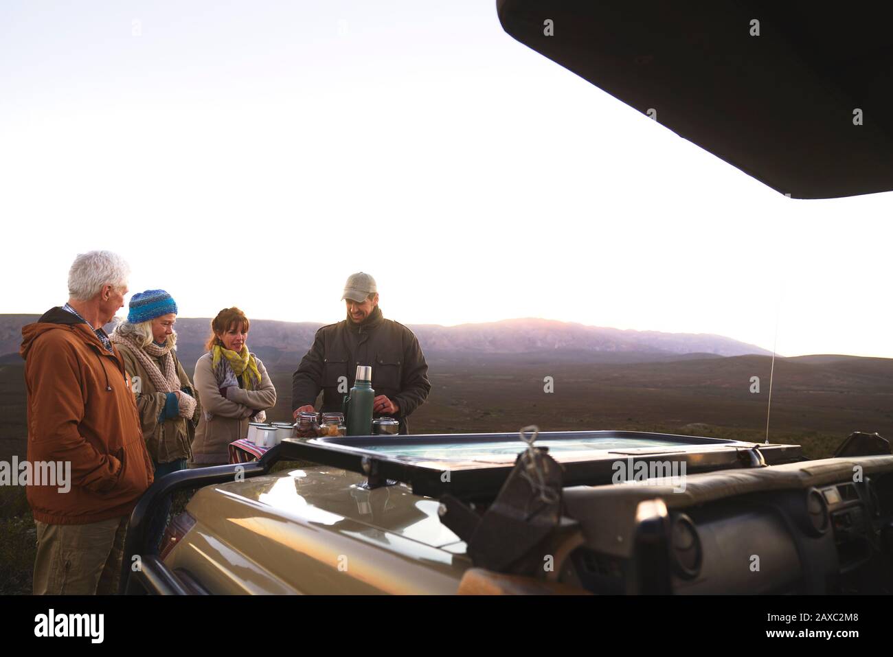 Safari-Reiseführer und Gruppen, die Kaffee außerhalb des Geländewagens genießen Stockfoto