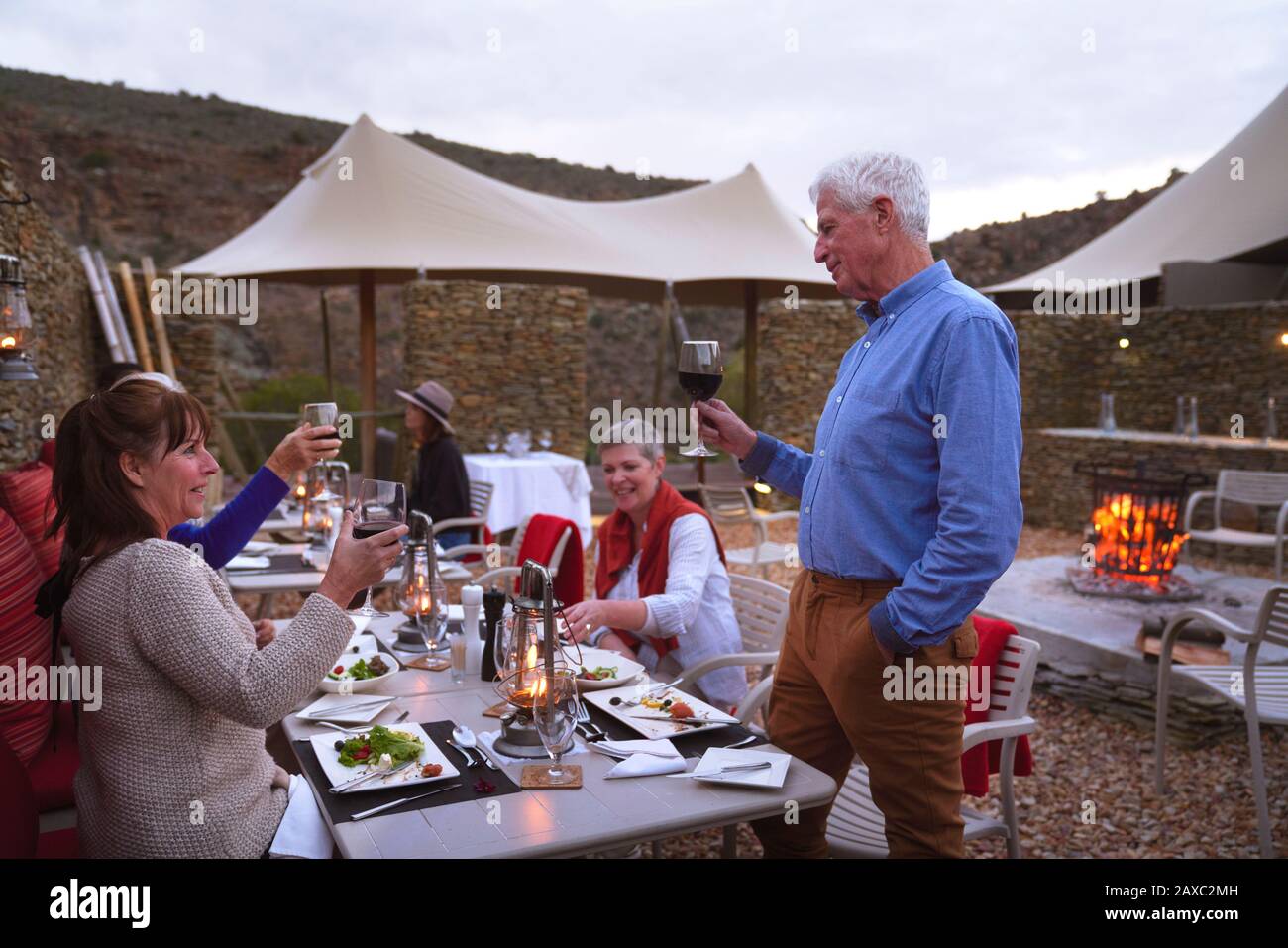 Senior man mit weinrötendem Freundeskreis, der auf der Terrasse des Restaurants speisen kann Stockfoto