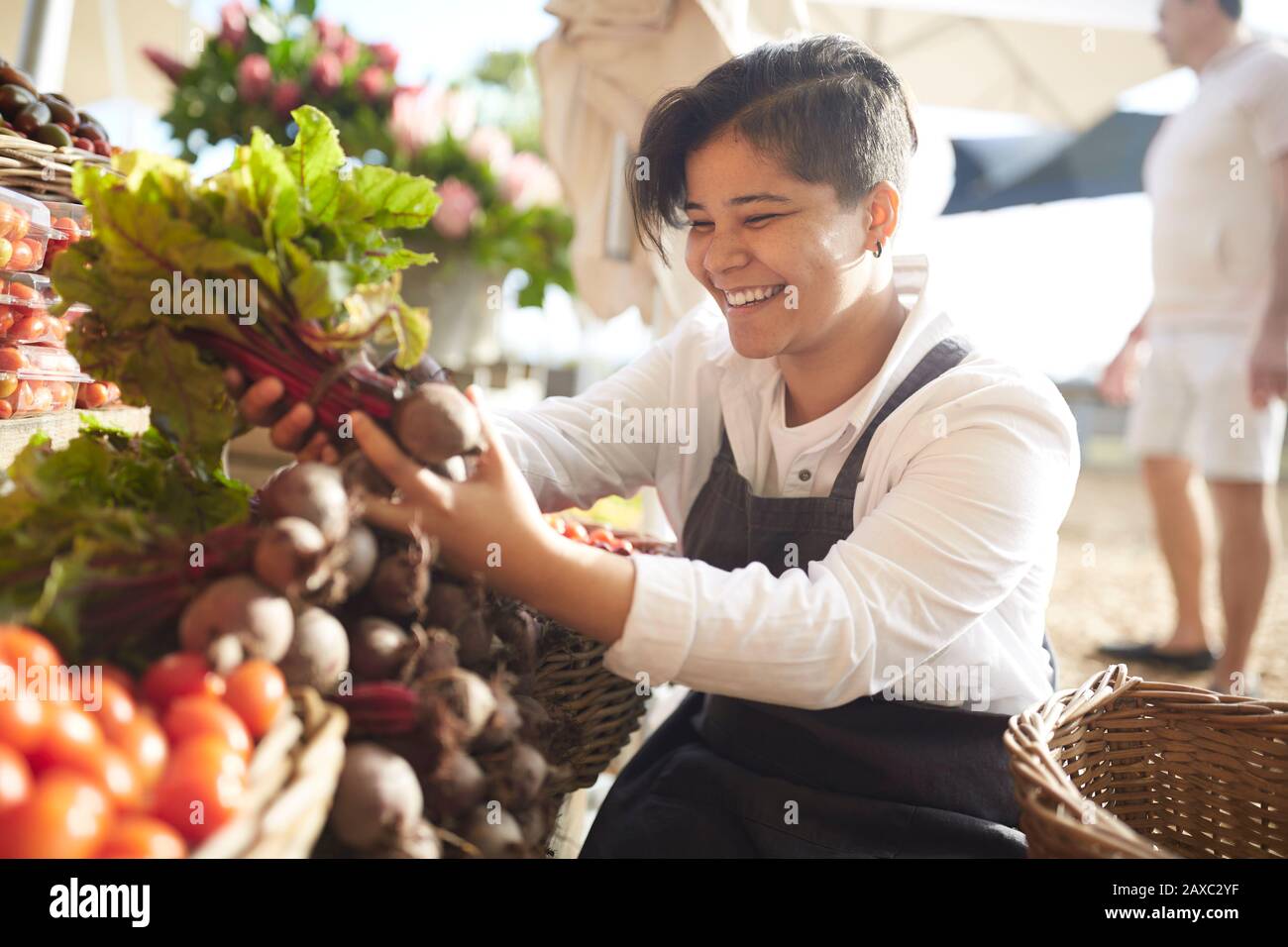 Lächelnde junge Frau, die arbeitet und Produkte auf dem Bauernmarkt arrangiert Stockfoto