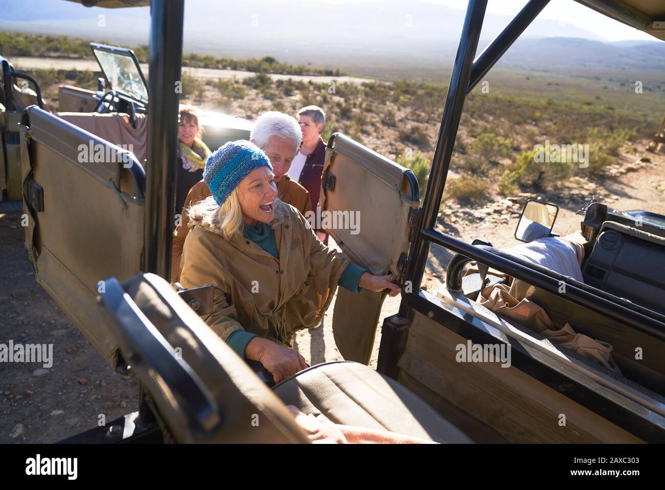 Glückliche ältere Frau, die in ein Geländefahrzeug mit Safari einsteigen kann Stockfoto