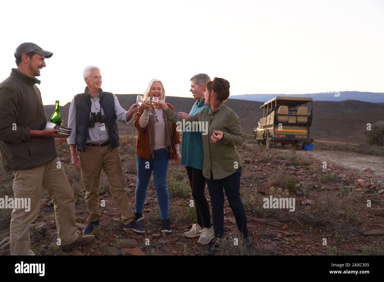 Fröhliche Safari-Tour-Gruppe, die Champagner trinkt Stockfoto