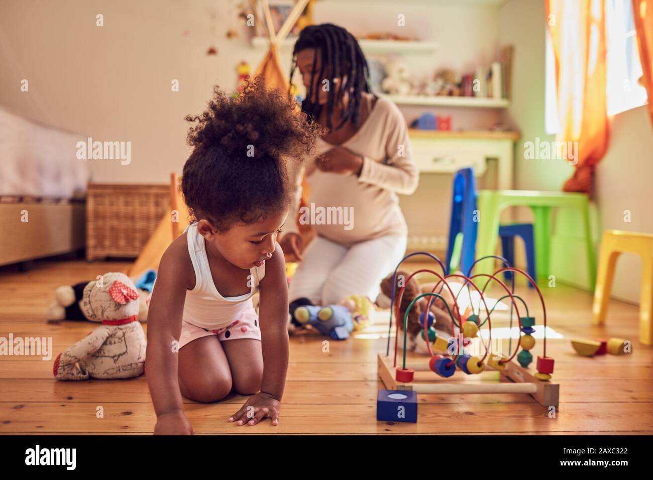 Schwangere Mutter und Tochter, die mit Spielzeug spielen Stockfoto