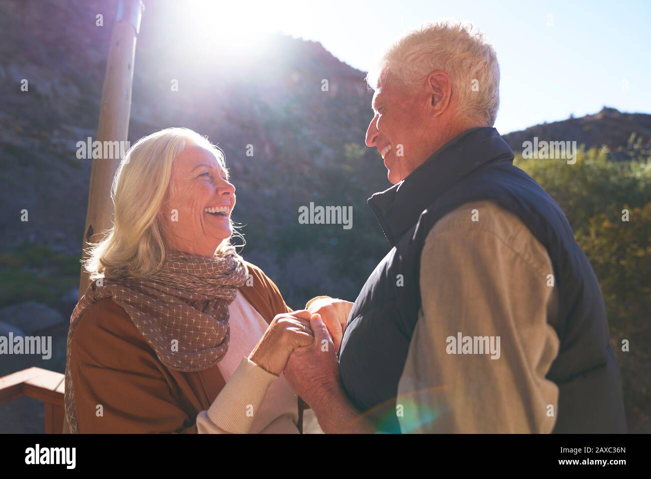 Glückliches älteres Paar hält die Hände auf dem sonnigen Balkon Stockfoto