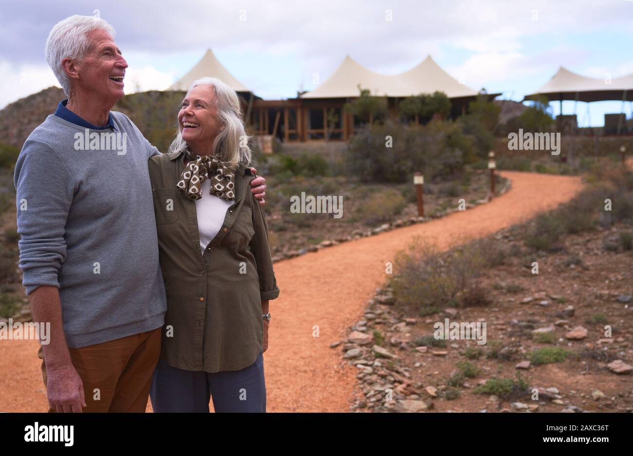Glückliches älteres Paar auf dem Fußweg vor der Safarihütte Stockfoto