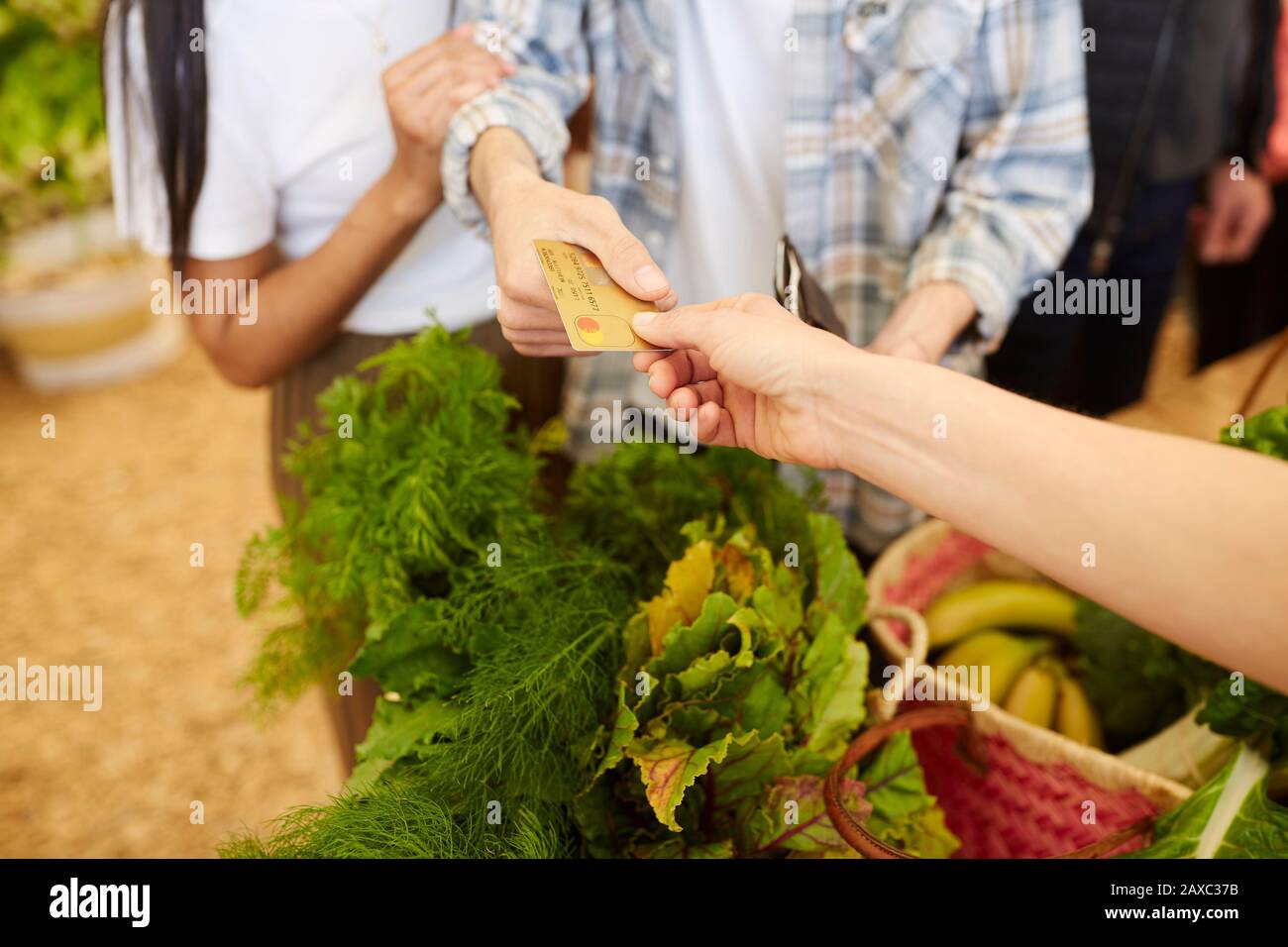 Kunden, die Gemüse mit Kreditkarte auf dem Bauernmarkt bezahlen Stockfoto
