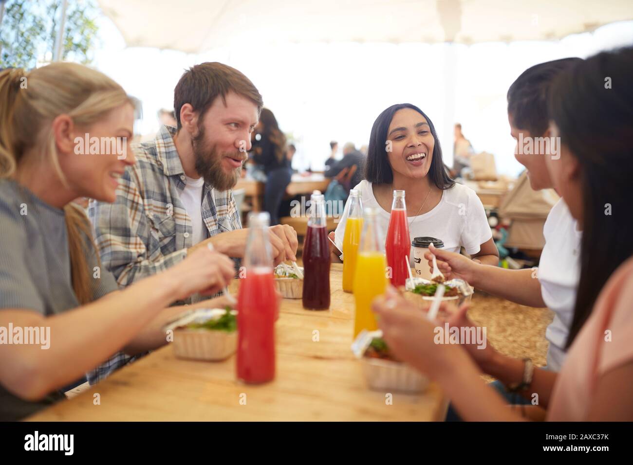 Lächelnde Freunde genießen Mittagessen auf dem Bauernmarkt Stockfoto