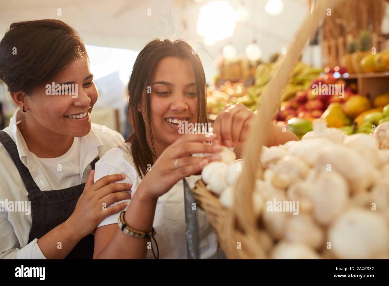 Lächelnde Frauen, die Knoblauch auf dem Bauernmarkt arrangieren Stockfoto