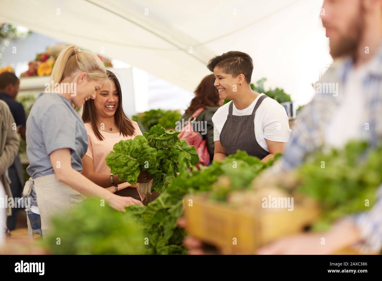 Frauen, die arbeiten und Gemüse auf dem Bauernmarkt arrangieren Stockfoto
