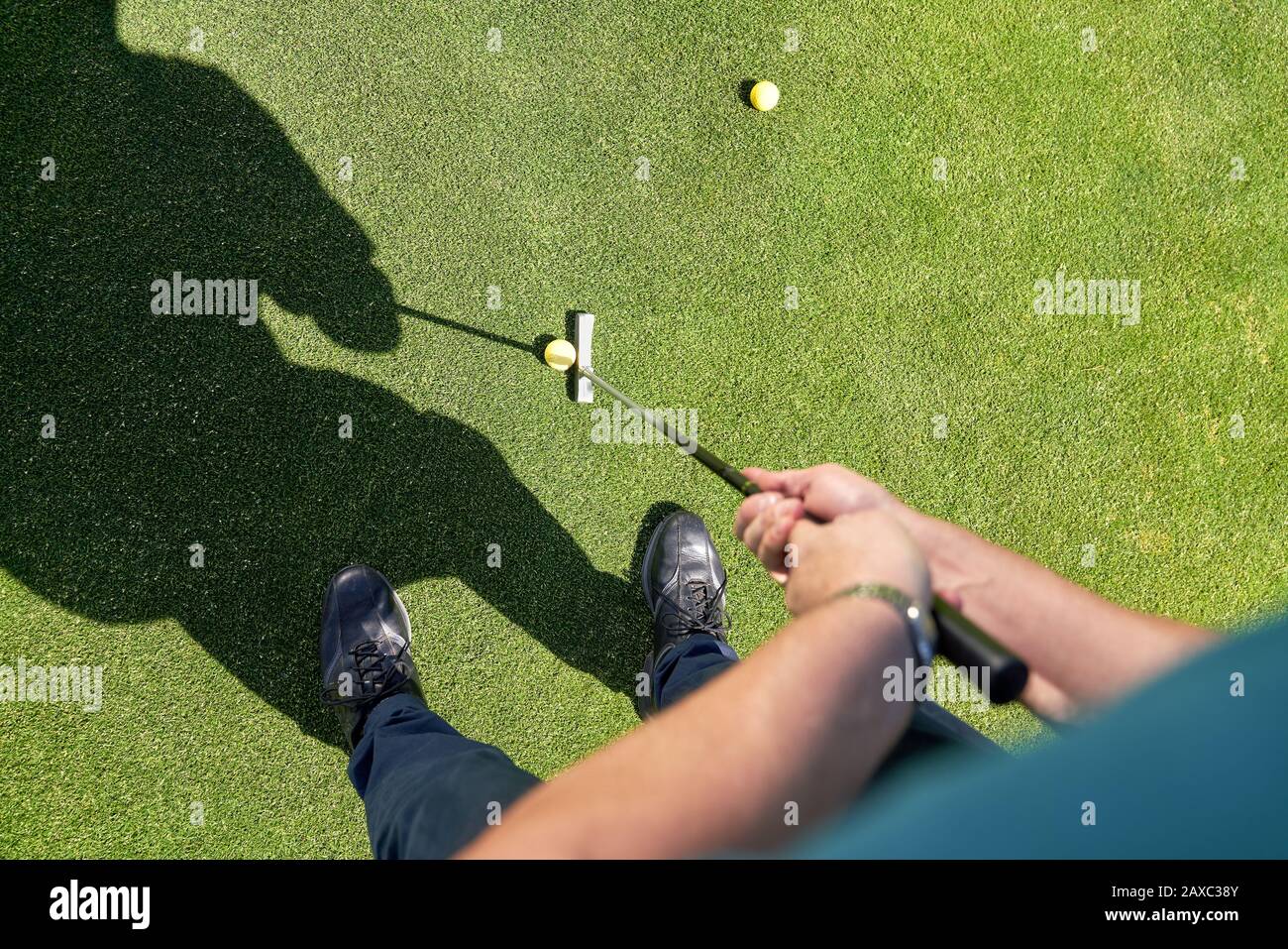 Blickpunkt der Mann, der Golfball auf sonnige Grüns legt Stockfoto