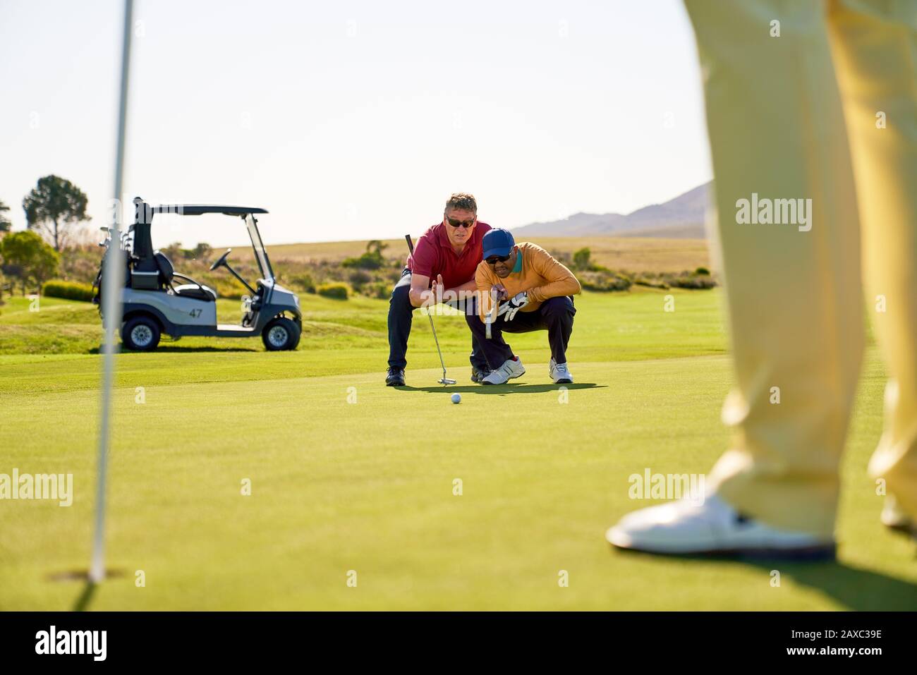 Männliche Golfer planen auf sonnigen Golfgrüns Stockfoto