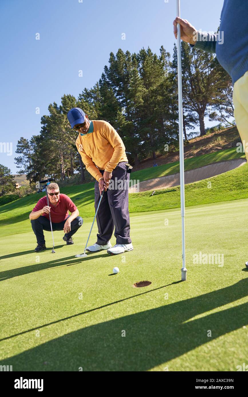 Männlicher Golfer, der sonnige Golfgrüns einlegt Stockfoto