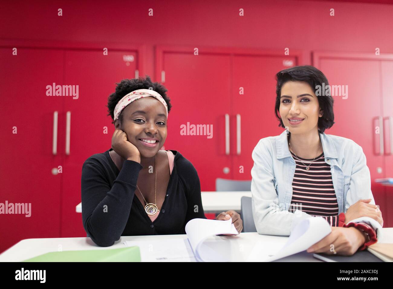 Portrait selbstbewusste, lächelnde Studenten der Community College mit Schreibarbeit im Klassenzimmer Stockfoto