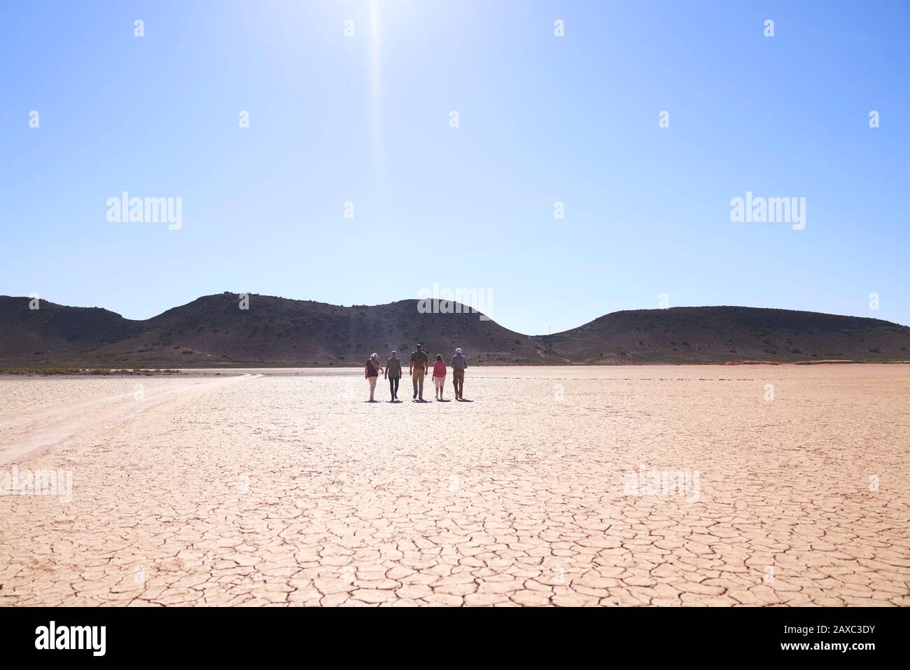 Safari-Tour-Gruppe, die auf der sonnigen, rissigen Erde Südafrikas spazieren geht Stockfoto