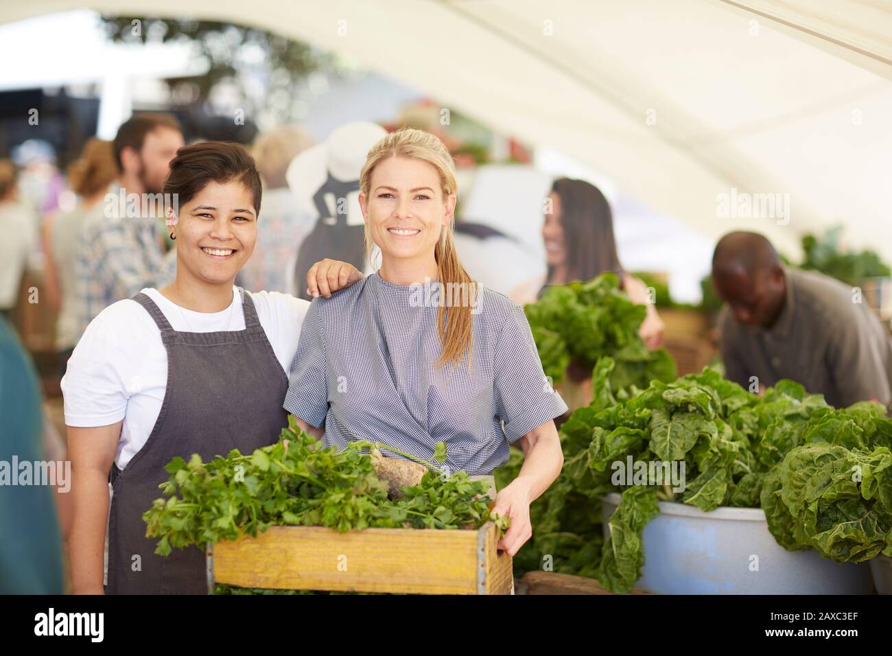 Portrait lächelnde Frauen Arbeiter mit Gemüsekiste auf dem Bauernmarkt Stockfoto