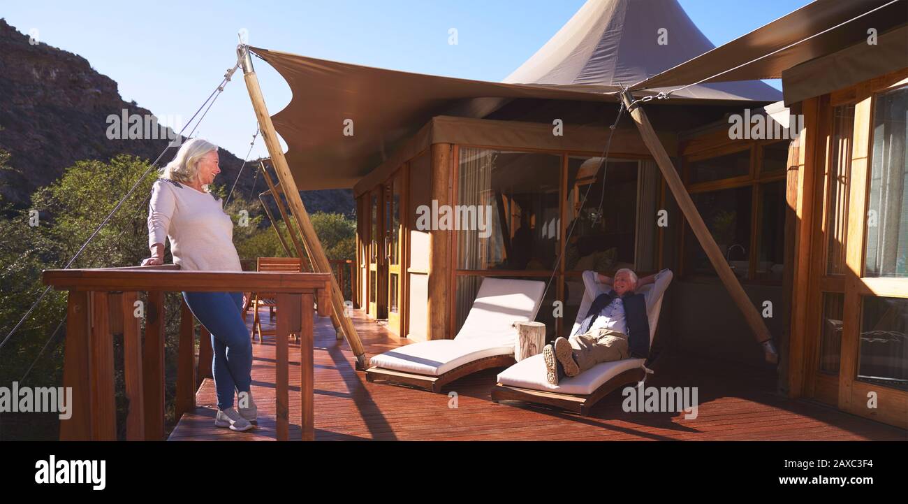 Sorgenfreies älteres Paar, das sich auf dem sonnigen Luxussafari Lodge Balkon entspannen kann Stockfoto