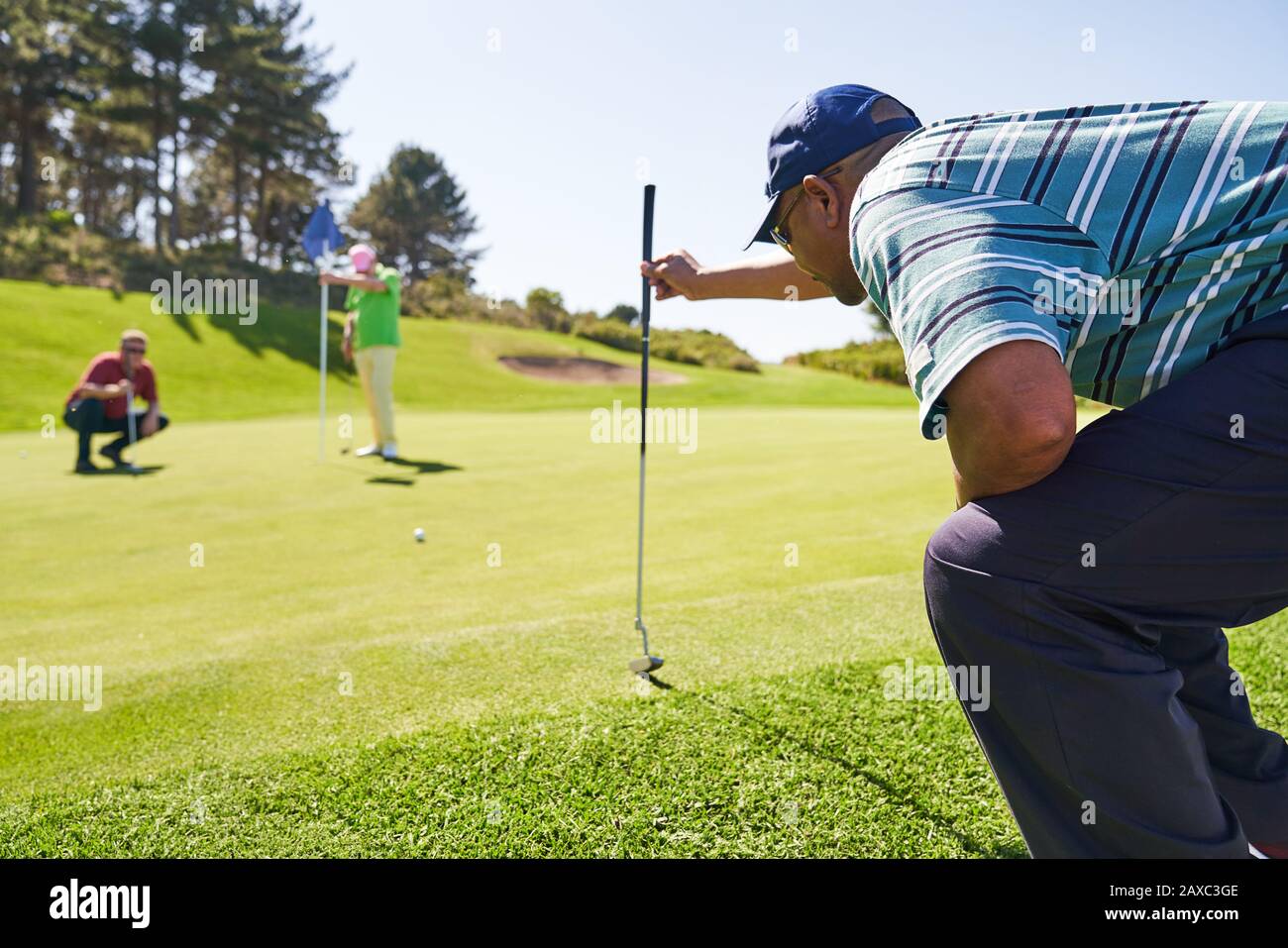 Männlicher Golfer, der sich auf einem sonnigen Golfplatz abputzt Stockfoto
